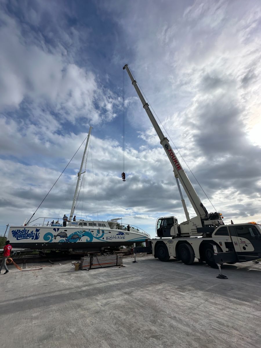 Crane stepping the mast on a large charter catamaran in the yard