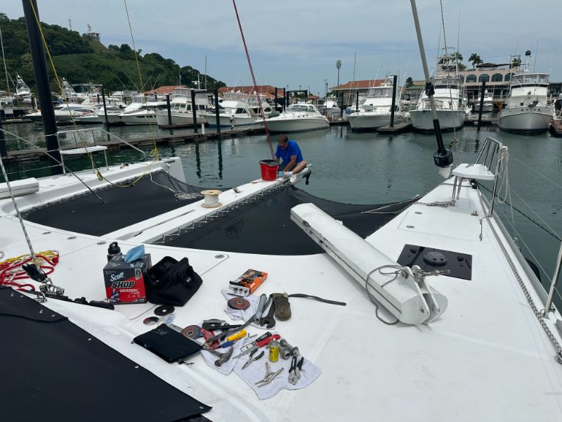 Tools laid out on a catamaran foredeck during bowsprit and trampoline work